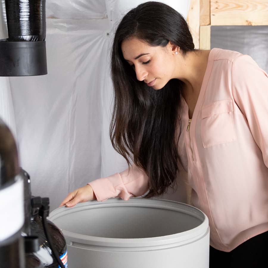 Woman checking water softener salt level in brine drum